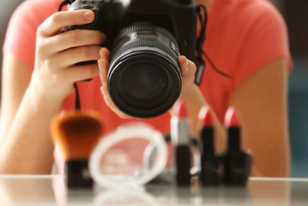 Product Photography: Young woman taking closeup pictures of makeup kit
