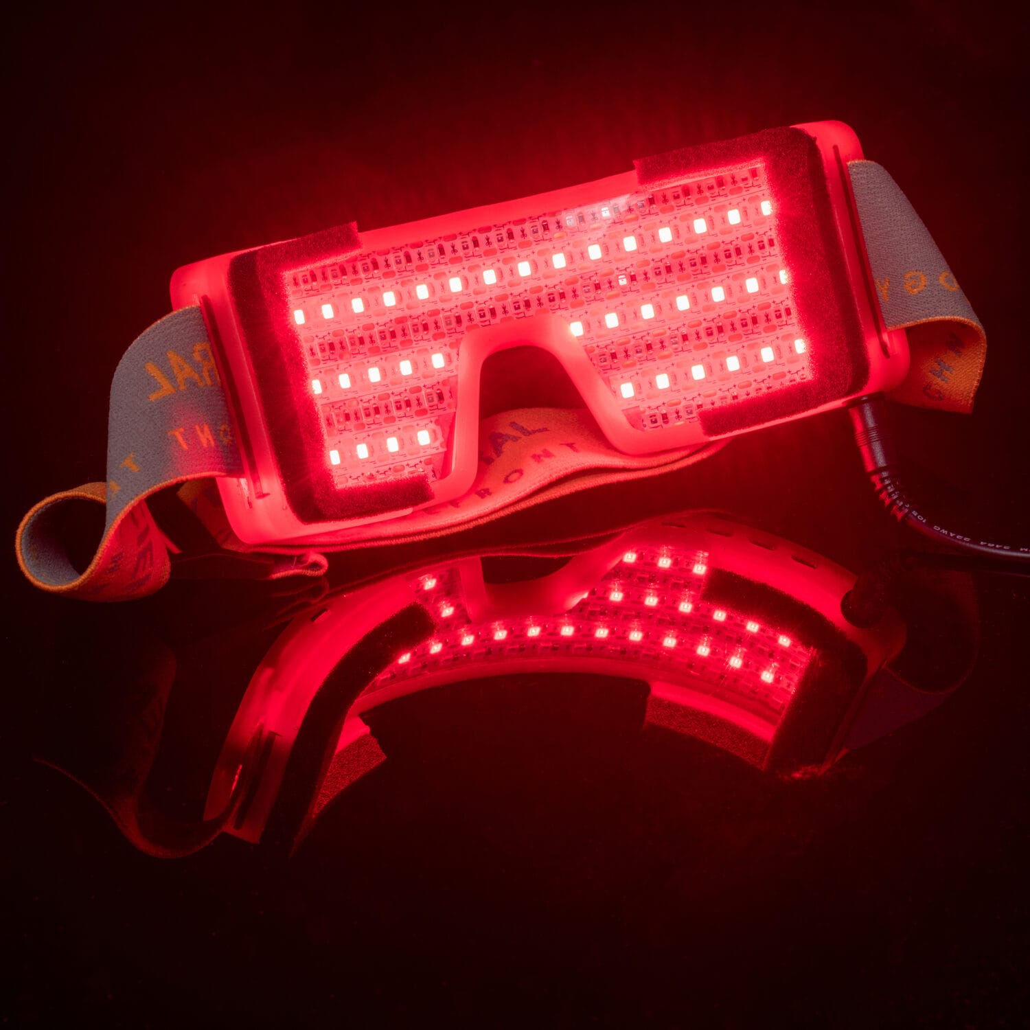 Dramatic hero image of red light therapy goggles glowing against a black background — high-impact Amazon product photo by Jules Design, Toronto studio for bold e-commerce branding.